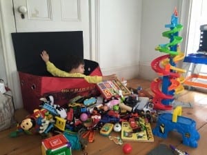 kid with toys outside of toy box