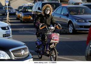 a-lady-rides-an-electric-bicycle-on-road-packed-with-cars-in-beijing-c159mr