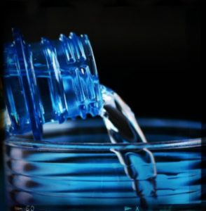 bottle pouring water into a cup