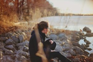 inner critic, anxiety, guilt, fear, lonely, woman sitting on rocks