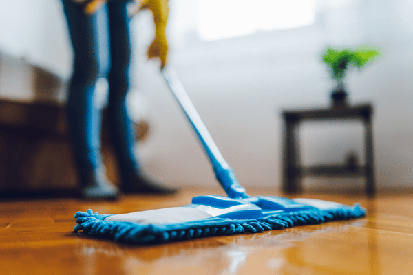 A stay-at-home mom cleans floors with a swiffer while her kids are at school.