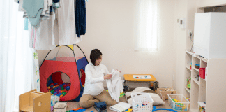 My Life as a Stay at Home Mom with School Aged Children A stay-at-home mom folds clothing in a messy play room while her kids are not home.