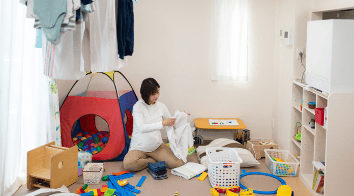 My Life as a Stay at Home Mom with School Aged Children A stay-at-home mom folds clothing in a messy play room while her kids are not home.