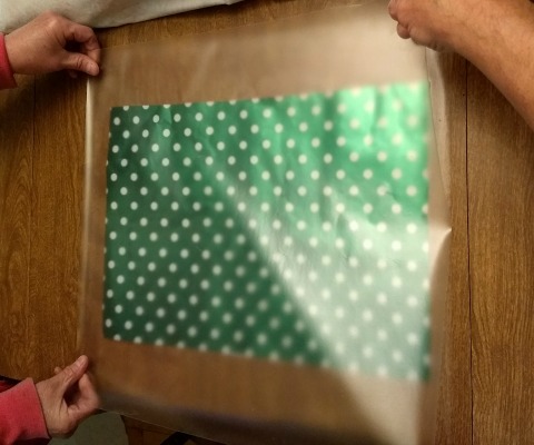 Laminating wrapping paper for a holiday placemat.
