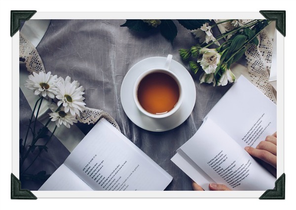 a cup of coffee, flowers, and a book