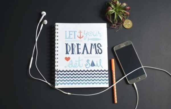 5 Women Focused Podcasts to Inspire Mom Bosses phone and notebook on desk