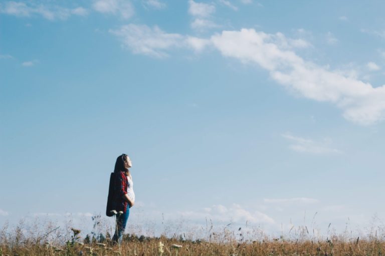pregnant woman standing in field with blue sky