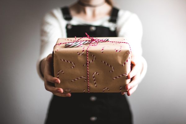 Holiday Service Activities: How My Family Can Spread Holiday Kindness Person holding out wrapped Christmas present