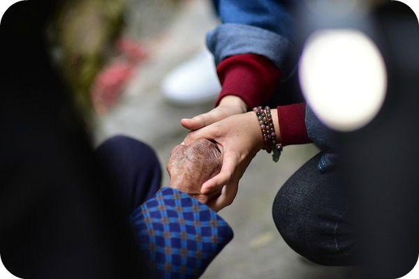 a member of the sandwich generation holding hands with their parent