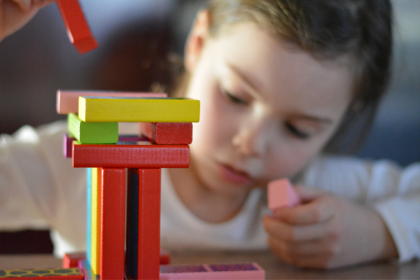 girl stacking multicolored wooden blocks