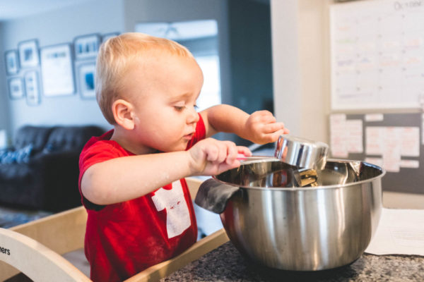 Five Favorite Muffin Recipes to Bake with Your Child toddler measuring preparing to make one of our favorite muffin recipes