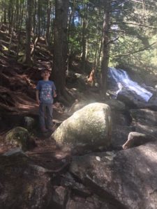 boy near waterfall in the woods
