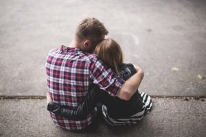 A man and a woman sitting and embracing.