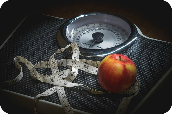 an apple and tape measure on a scale