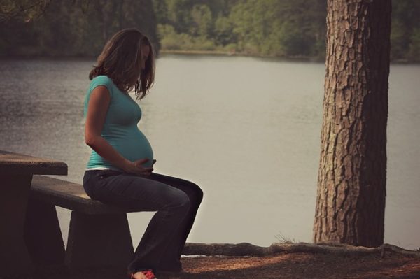 pregnant woman sitting by lake