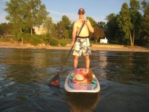 man paddleboarding with a disabled child on his board.