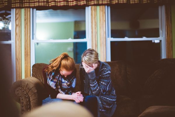 two women holding hands and crying