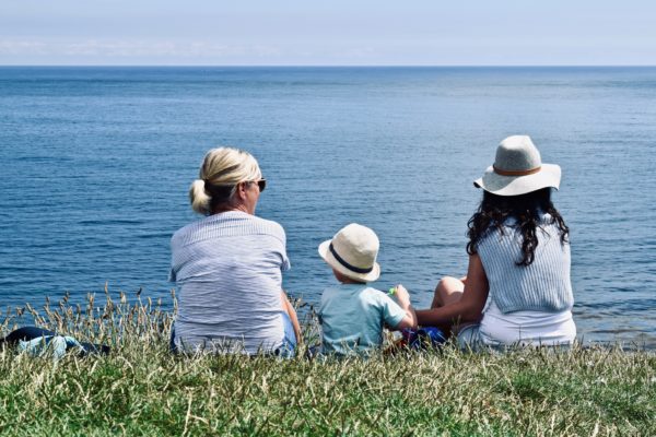 two women and a child sit overlooking the ocean