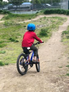 boy in red shirt on a bike on a dirt path