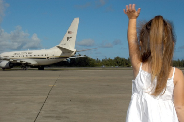 girl in white dress waves to a plane