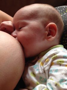 Caucasian baby nursing from mother's breast during breastfeeding journey