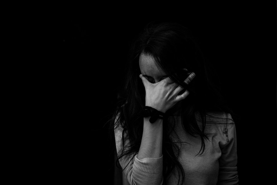 A black and white image of a woman with her hand over her face.