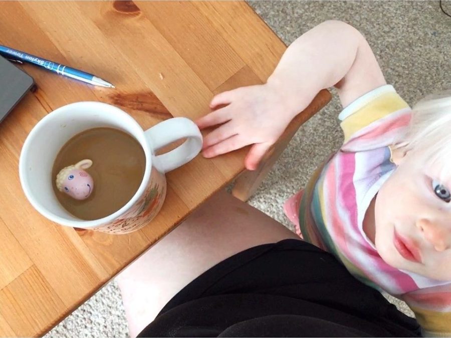 Work From Home Mom: Six Tips for Making Work Happen with a Toddler Viewed from above, a toddler places a toy sheep in her mothers coffee.