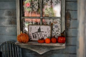 window with pumpkins and sign that says "the witch is in."
