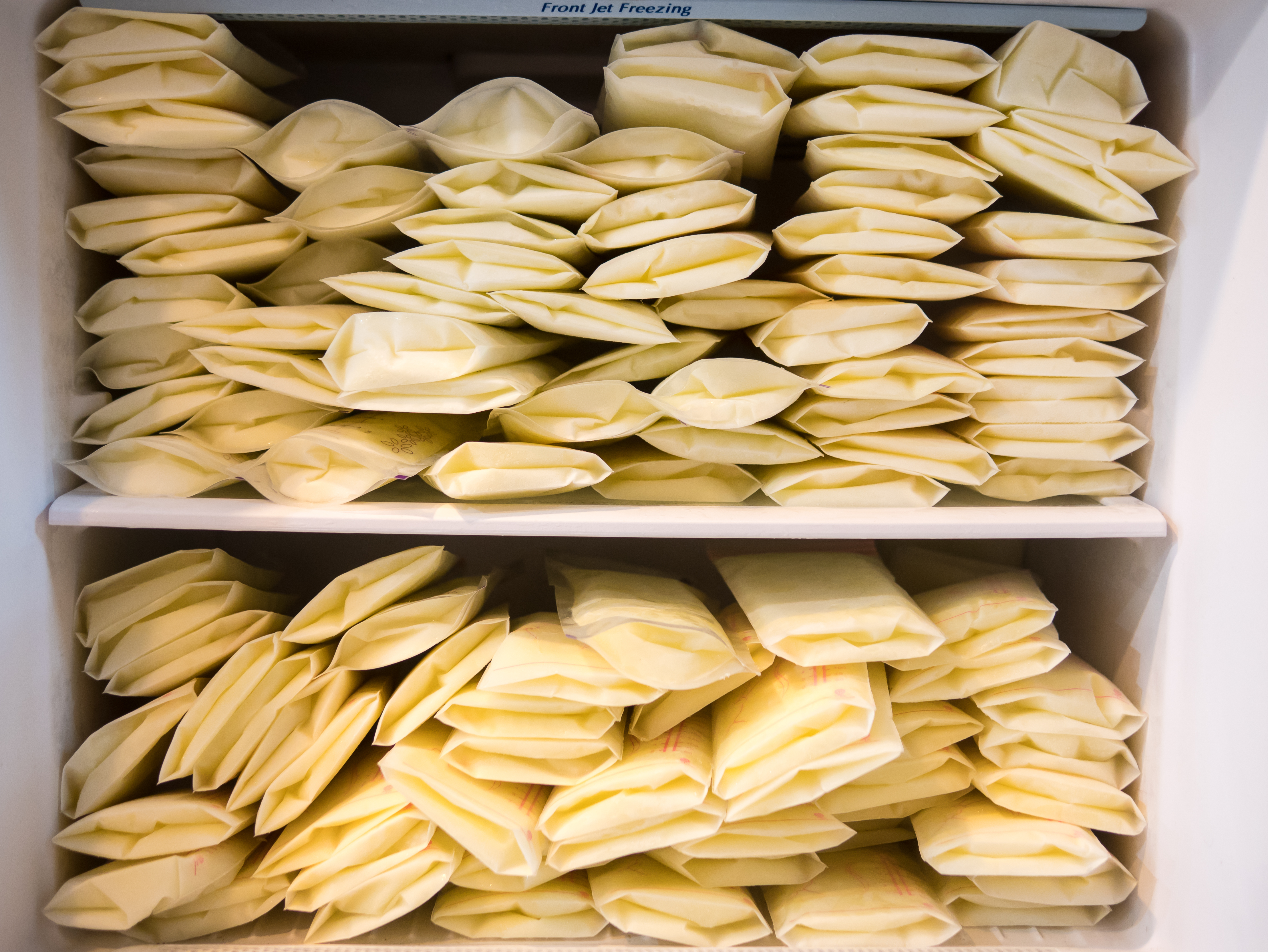 breast milk in milk storage bags filling a freezer