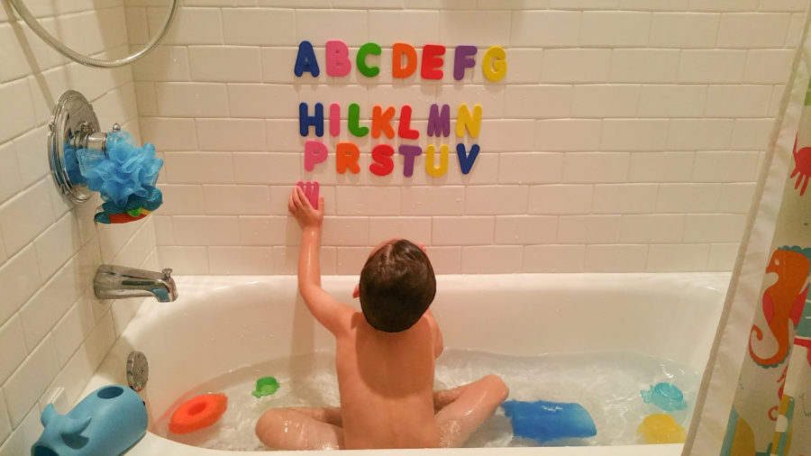 Foolproof Bath Bombs You Can Make with Your Kids boy playing with alphabet letters while sitting in the bath