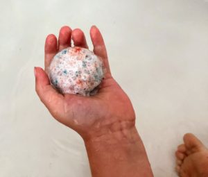 a small child's hand holding a fizzing ball