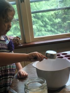 A girl is pouring ingredients into a large bowl