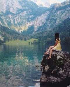 girl sitting on a rock overlooking a lake