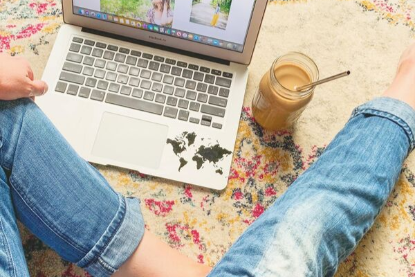 legs and computer and cup of coffee with a straw. Woman blogger chasing her dream job.