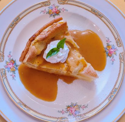 Slice of pear and cardamom custard bake with apple cider sauce.