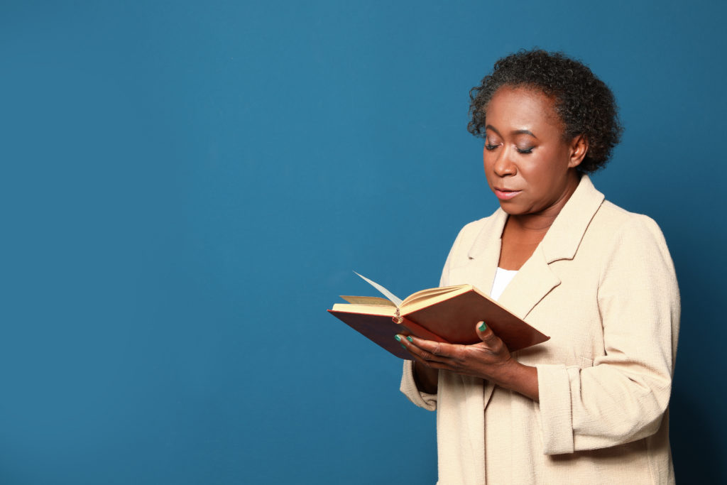 middle aged black woman in beige suit jacket reading a book
