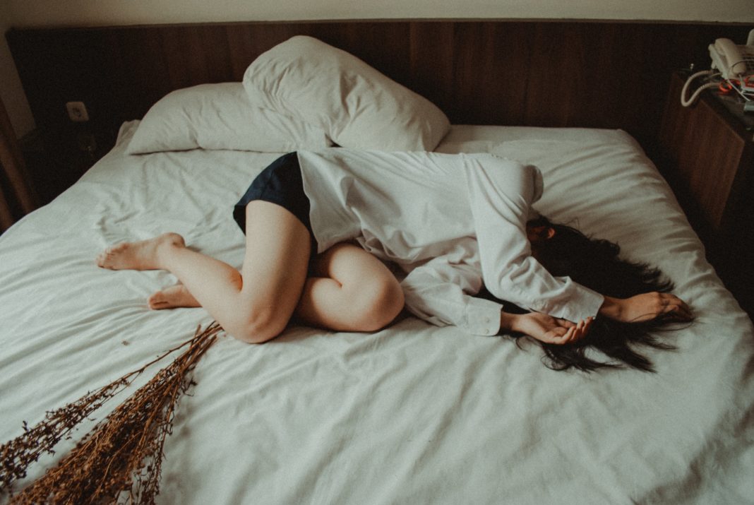 Teaching My Daughters about the Toll of the Emotional Symptoms of Menstruation Woman lying in the fetal position on a bed