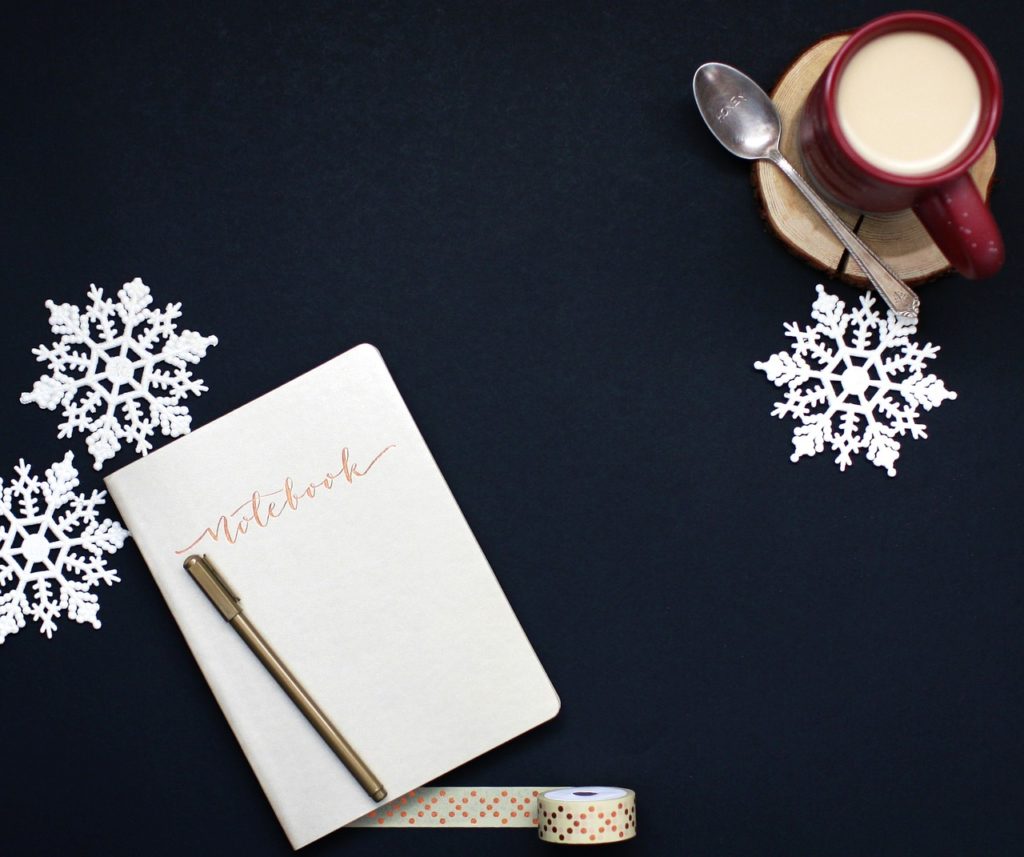 A notebook and cup of coffee viewed from above.