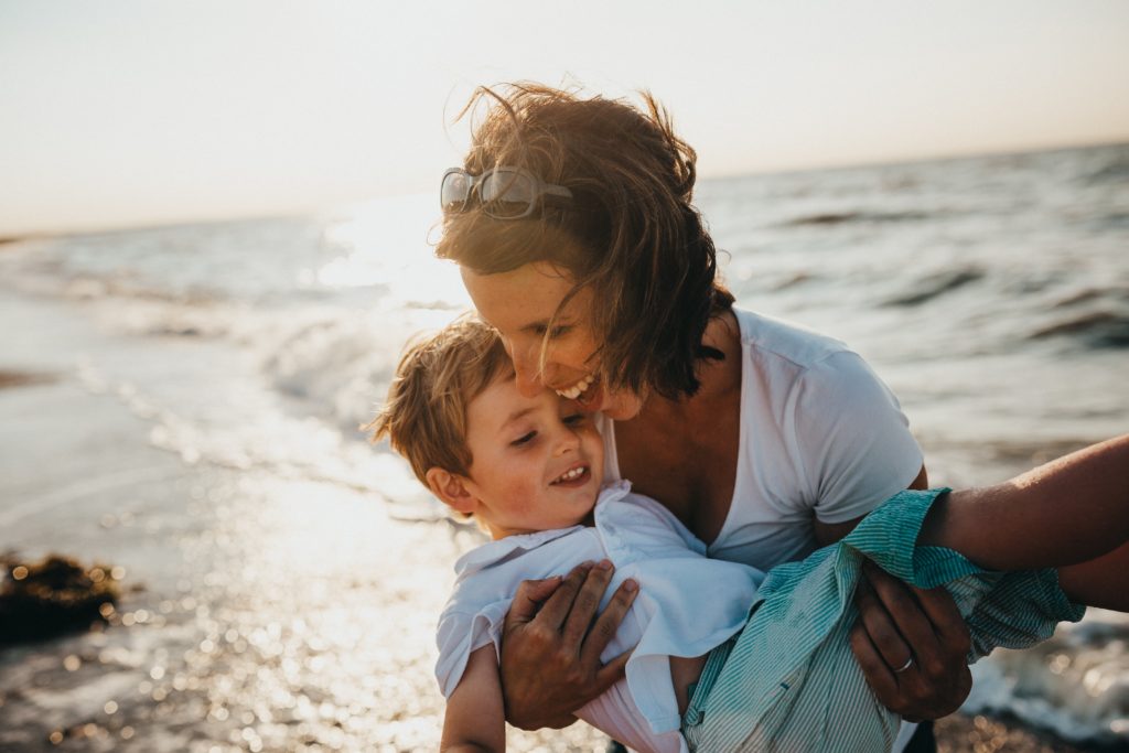 A mother hugs her toddler at the beach
