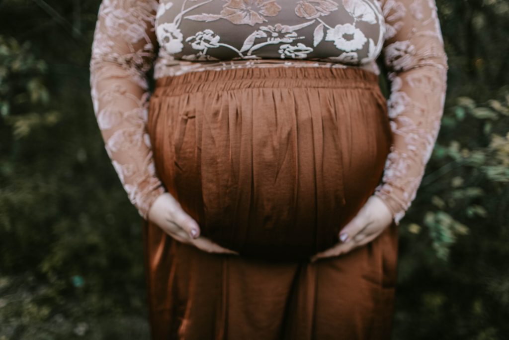 Pregnant woman holding her belly outdoors.