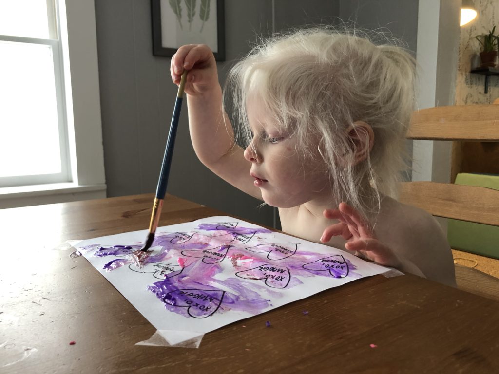A toddler painting at a table