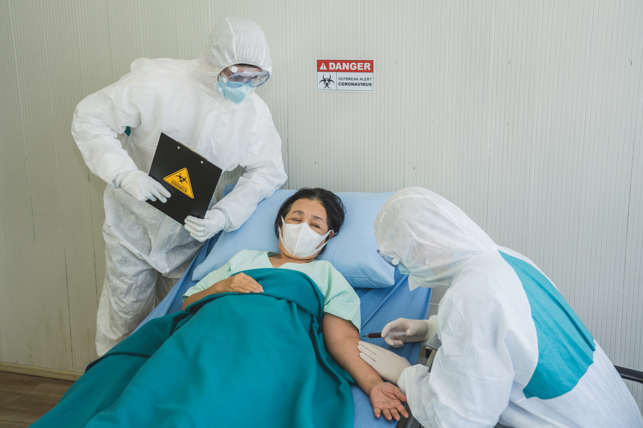 medical care staff in personal protective equipment taking care of a sick patient