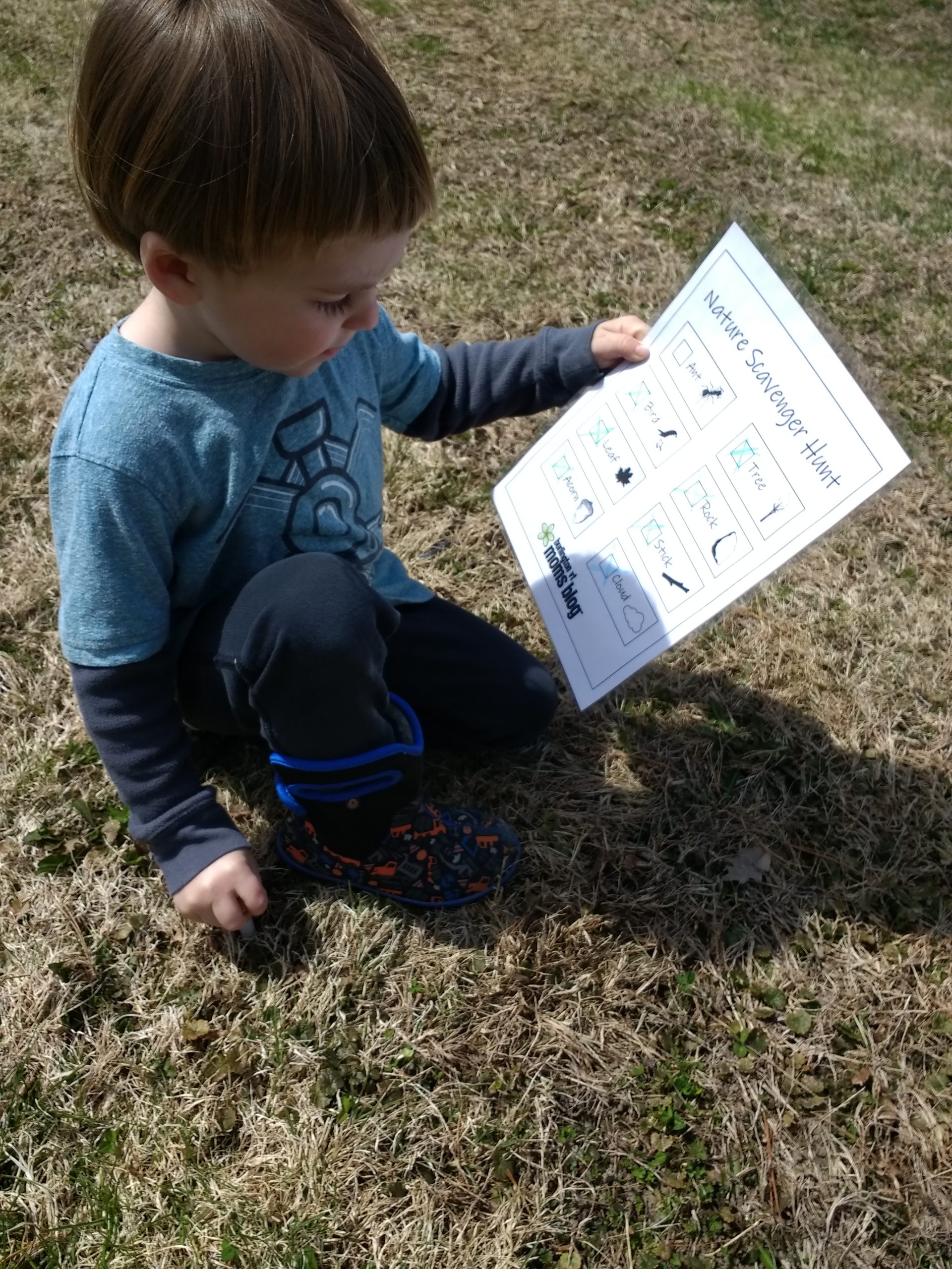 child hold page of scavenger hunt- this is one of five screen-free hands-on toddler activities