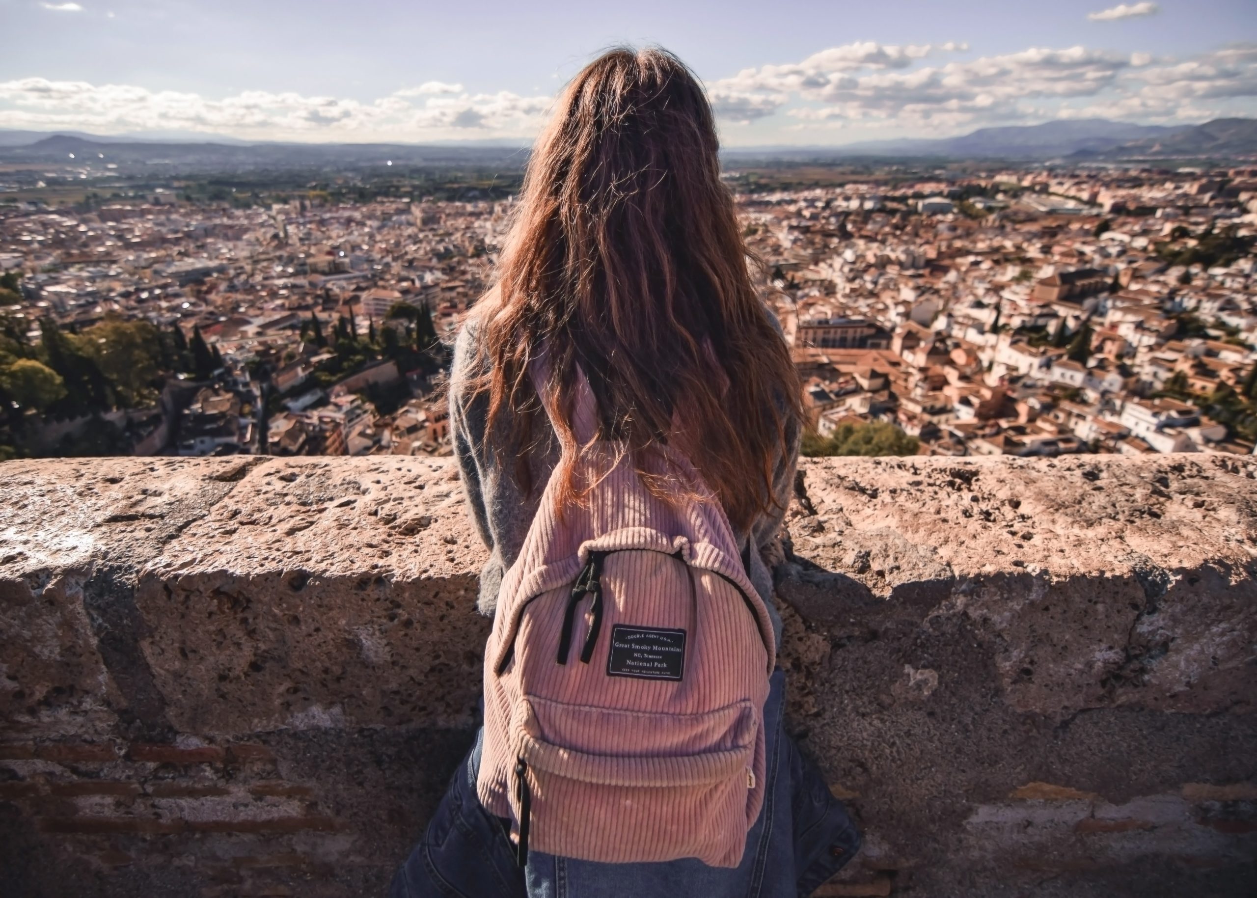 girl with pink backpack looking out over city
