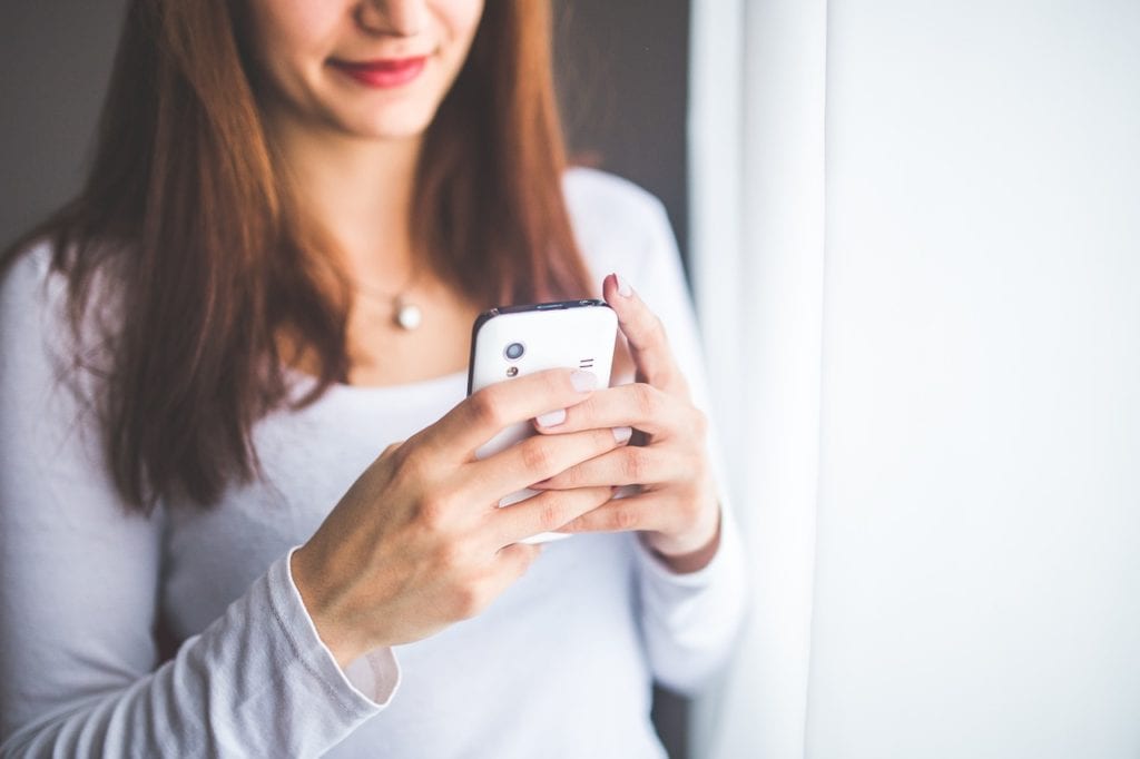 A woman texting on a coll phone