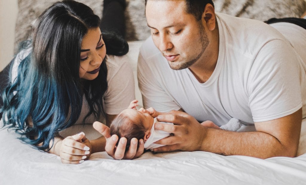 photo of couple looking down at their newborn