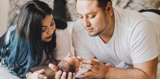 Tried and True Affordable Newborn Must-haves photo of couple looking down at their newborn