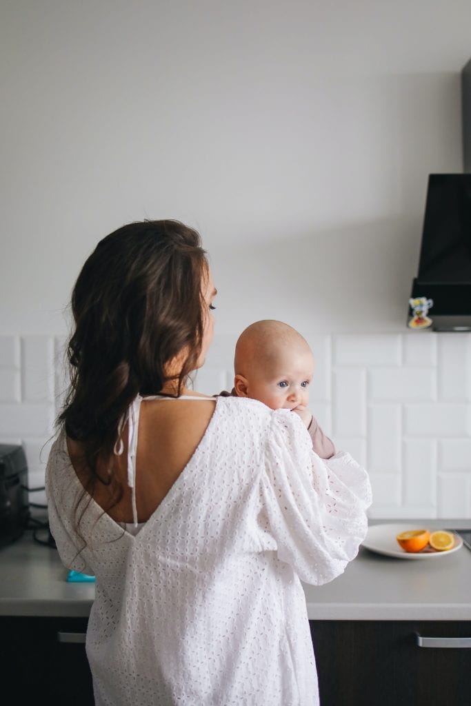 woman in white tank top carrying a baby
