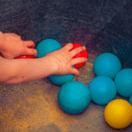 child grabbing blue and red balls