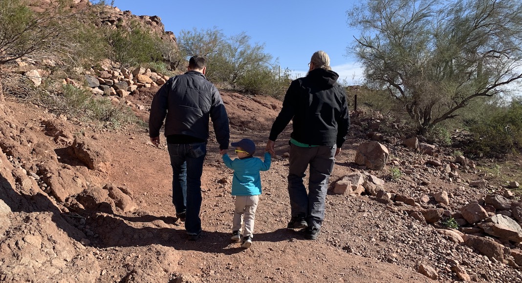 little boy holding hands with dad and grandpa